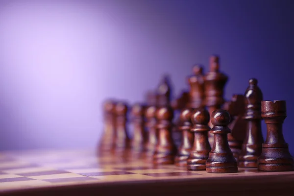 Pedaços de xadrez e tabuleiro de jogo em fundo roxo desfocado — Fotografia de Stock