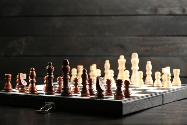 Piezas de ajedrez y tablero de juego sobre fondo de madera — Foto de Stock