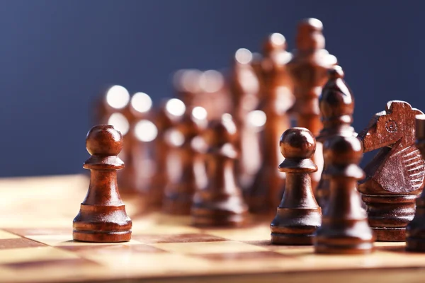 Piezas de ajedrez y tablero de juego sobre fondo azul oscuro —  Fotos de Stock