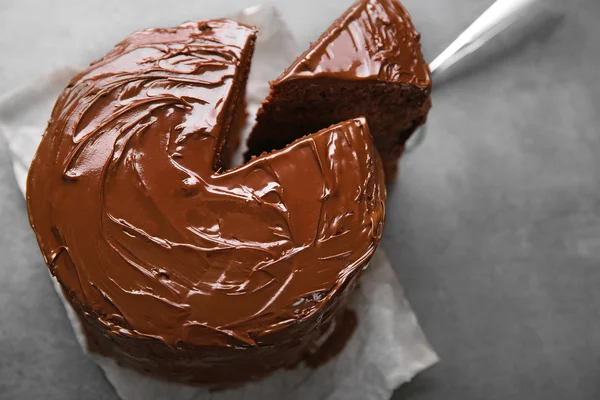 Schokoladenkuchen mit Schnittstück und Klinge auf grauem Hintergrund, Nahaufnahme — Stockfoto