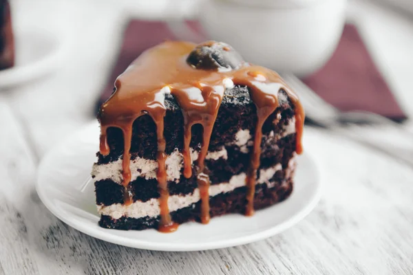 Pedaço de bolo de chocolate com caramelo na mesa de madeira closeup — Fotografia de Stock