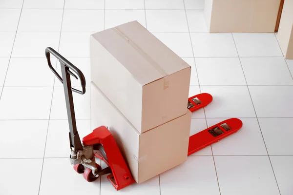 Fork pallet truck with stack of cardboard boxes — Stock Photo, Image