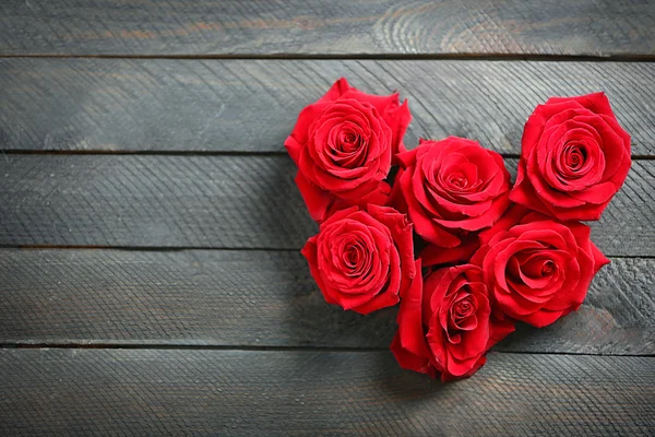 Brotes de rosas rojas frescas en forma de corazón sobre fondo de madera —  Fotos de Stock