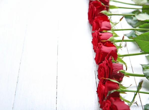 Wiersz o świeże czerwone róże na drewniane tła — Zdjęcie stockowe