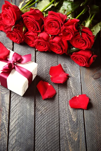 Bouquet di rose rosse fresche e scatola regalo su sfondo di legno — Foto Stock