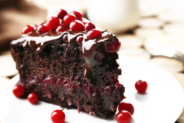 Piece of chocolate cake with cranberries on wooden background, closeup — Stock Photo, Image