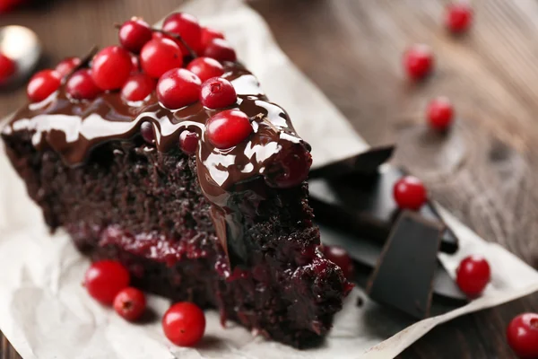 Pedaço de bolo de chocolate com cranberries em pergaminho, close-up — Fotografia de Stock