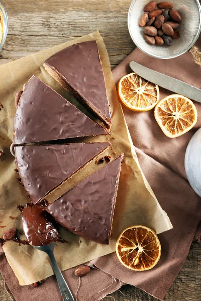 Sliced chocolate frosting cake on wooden table — Stock Photo, Image