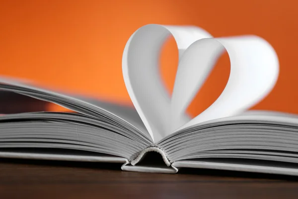 Heart from book pages on red blurred background — Stock Photo, Image