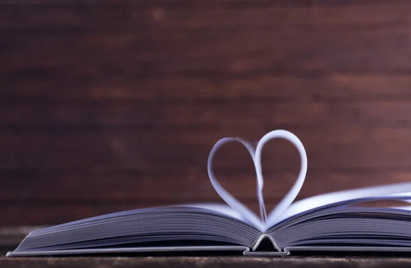 Serce ze stron książki na drewniane tło zamazane pole — Zdjęcie stockowe