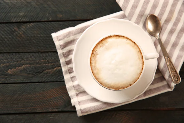 Secangkir cappuccino panas dengan busa dan sendok di atas meja kayu hitam — Stok Foto