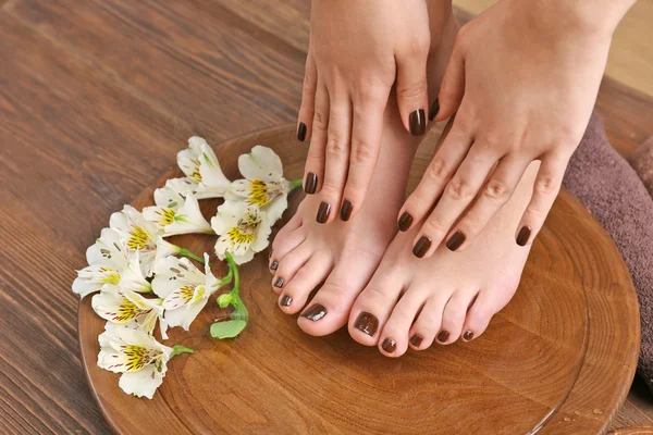 Gepflegte weibliche Füße und Hände in Wellness-Holzschale mit Blumen und Wasser Nahaufnahme — Stockfoto