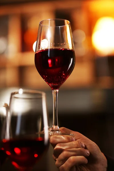 Male hand holding glass of wine in the bar — Stock Photo, Image