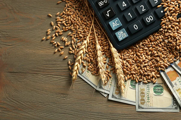 Billetes de dólar, calculadora y granos de trigo sobre fondo de madera. Concepto de renta agrícola —  Fotos de Stock