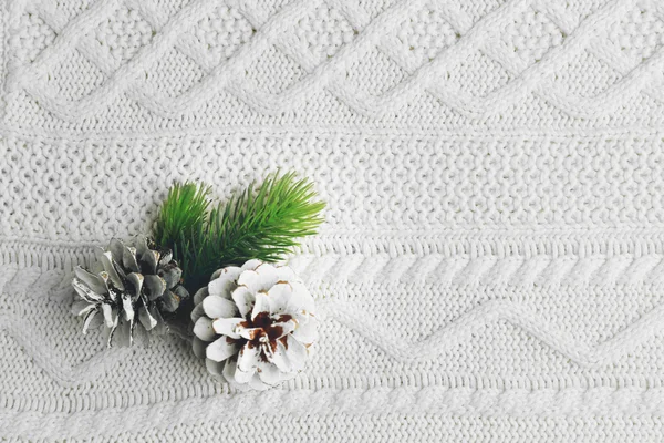 Hermoso fondo de invierno simple con conos de pino en textura de punto —  Fotos de Stock