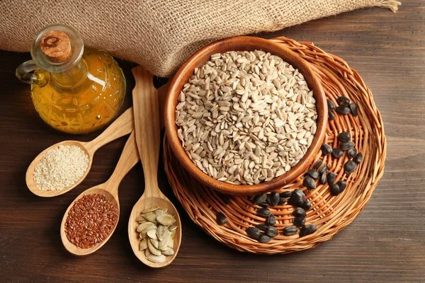 Sunflower oil and seeds on wooden table background, closeup — Stock Photo, Image