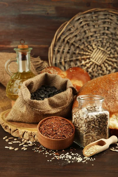 Composition of seeds , bread, buns and oil on wooden table background, closeup — Stock Photo, Image