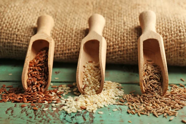 Varias semillas en cucharas de madera sobre fondo de madera verde, primer plano — Foto de Stock