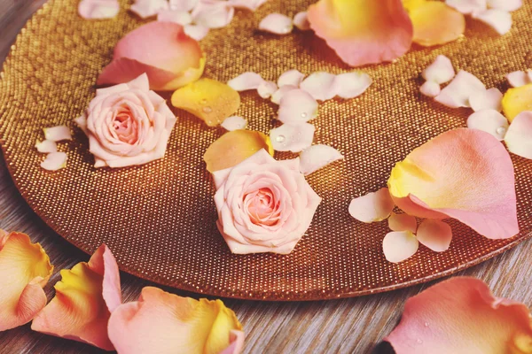 Rosa e amarelo pétalas de rosa em tigela dourada no fundo de madeira — Fotografia de Stock