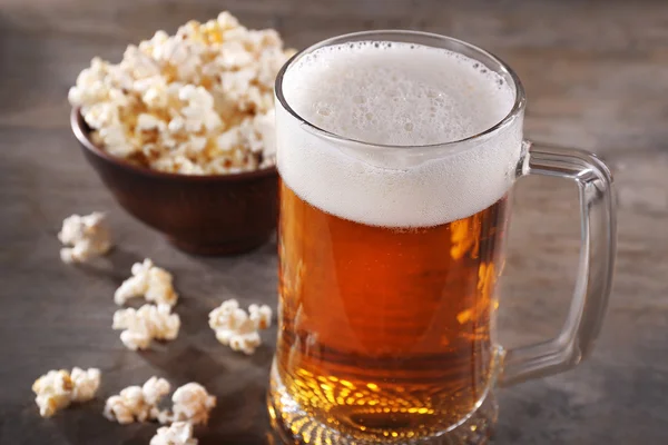 Glass mug of light beer with popcorn on wooden table, close up — Stock Photo, Image