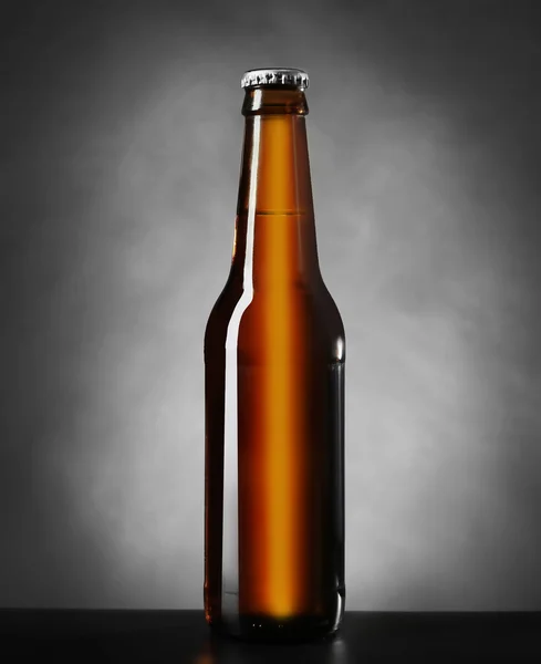 Ciemnej butelki piwa na szarym tle, z bliska — Zdjęcie stockowe