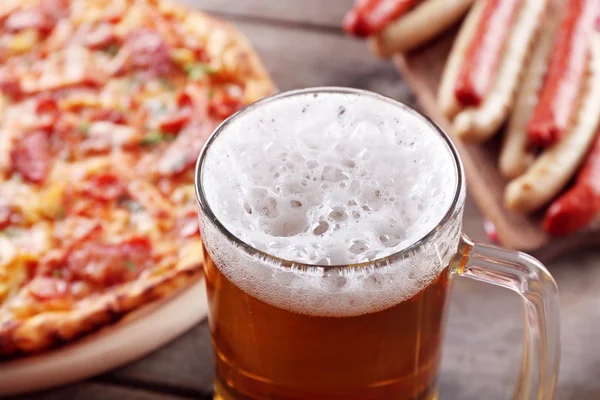 Embutidos a la parrilla, deliciosa pizza y vaso de cerveza sobre mesa de madera, de cerca — Foto de Stock