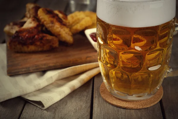 Vaso de cerveza y alitas de pollo sobre mesa de madera, de cerca —  Fotos de Stock