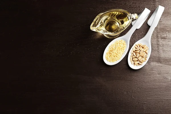 Girasole e semi di sesamo con olio su tavola di legno — Foto Stock