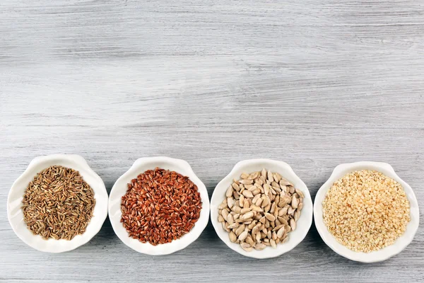 Diferentes tipos de sementes na tigela na mesa de madeira — Fotografia de Stock