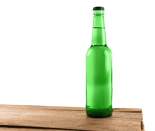 Yeşil cam bira şişesi üzerinde beyaz arka plan karşı ahşap tablo — Stok fotoğraf