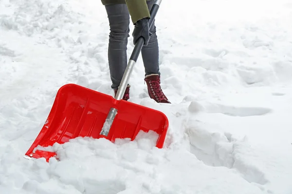 Concetto invernale. Donna rimozione neve con pala rossa — Foto Stock