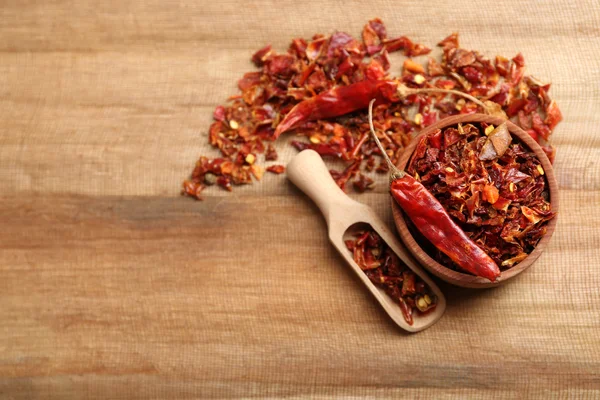 Crusher hot chili pepper on wooden table, top view — Stock Photo, Image