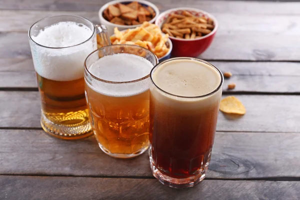 Verschiedene Biersorten und Snacks auf Holztisch — Stockfoto