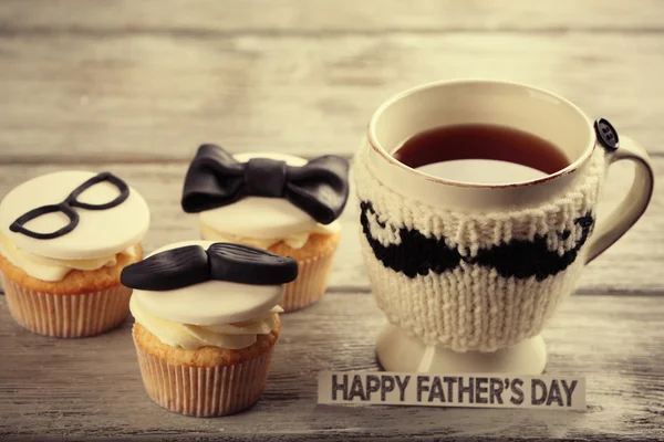 Deliciosos pastelitos creativos y una taza de té en una mesa de madera — Foto de Stock