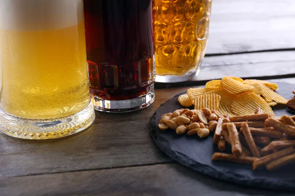 Various types of beer and snacks on wooden table — Stock Photo, Image