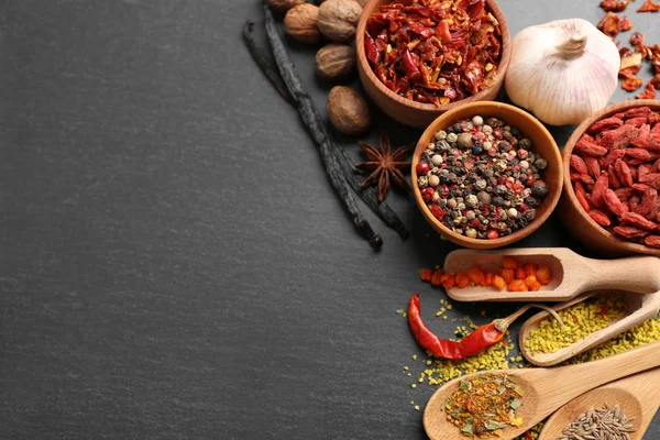 Assorted spices on black table background — Stock Photo, Image