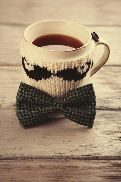 Pajarita y taza de té con bigote de punto sobre mesa de madera —  Fotos de Stock