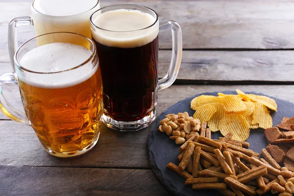 Vari tipi di birra e snack sul tavolo di legno — Foto Stock
