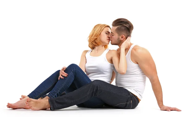 Молодая пара влюблённая целуется и сидит вместе, изолированная на белом — стоковое фото