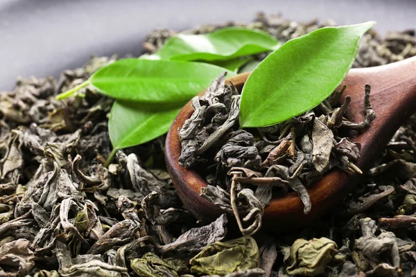 Té seco con cuchara de madera y hojas verdes, de cerca —  Fotos de Stock