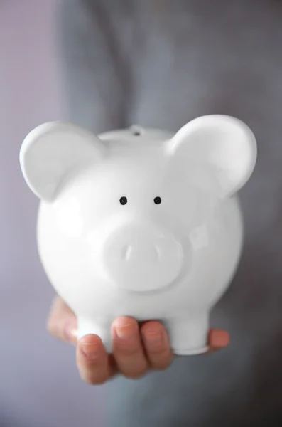 Woman holding in hand white piggy bank — Stock Photo, Image