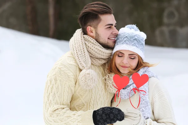 Jovem casal apaixonado segurando corações de papel vermelho ao ar livre no inverno — Fotografia de Stock