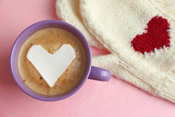 Cup of hot cappuccino with heart marshmallow and warm mittens on pink background, close up — Stock Photo, Image