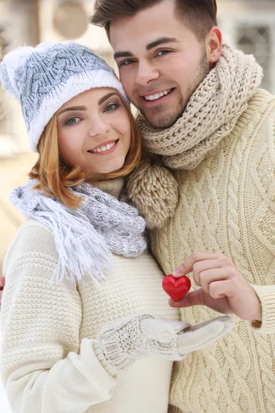 Ungt par i kärlek hålla litet rött hjärta utomhus på vintern — Stockfoto