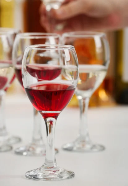 Lunettes avec différents types de vin et main humaine tenant des verres à vin en arrière-plan — Photo