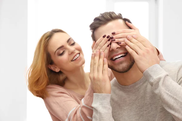 Junge Frau schließt die Augen ihres Freundes am Fenster — Stockfoto