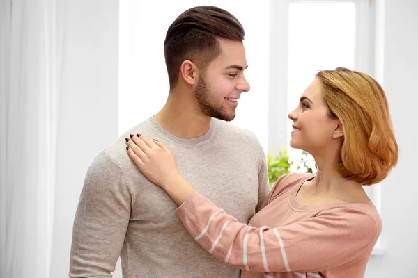 Young couple in love looking at each other beside the window — Stock Photo, Image