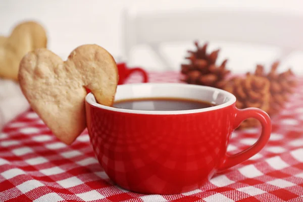 Печенье в форме сердца на чашке кофе на клетчатой салфетке крупным планом — стоковое фото