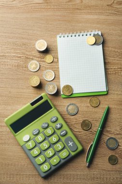 Para kavramı. Sikke ve ahşap masa üstünde defter ile yeşil hesap makinası