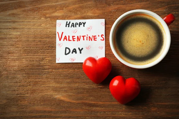 情人节的概念。杯咖啡，两个红心和木桌背景的注记 — 图库照片